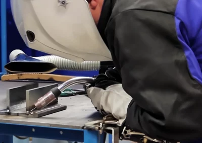 Skilled welder performing precision metalwork under bright light of welding torch, mechanical testing services